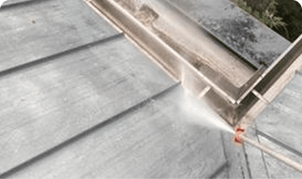 Power washing a metal rooftop corner.