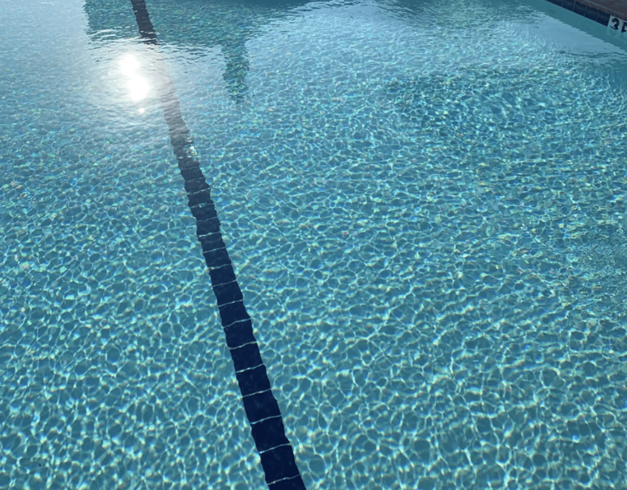 Clear swimming pool water with sunlight reflection.