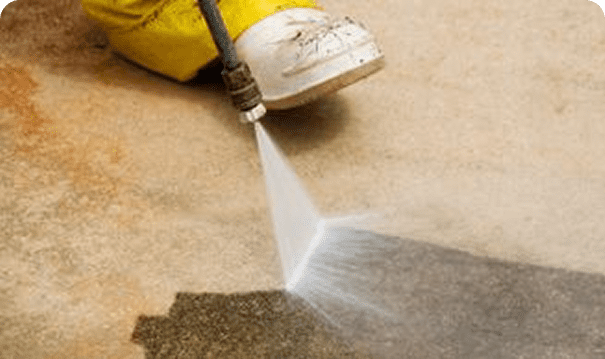Pressure washing a concrete surface with water.