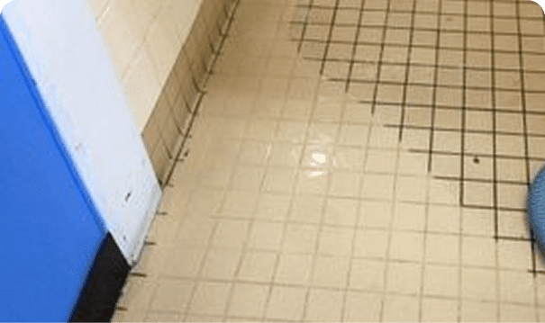 Partially cleaned tiled floor with blue object.