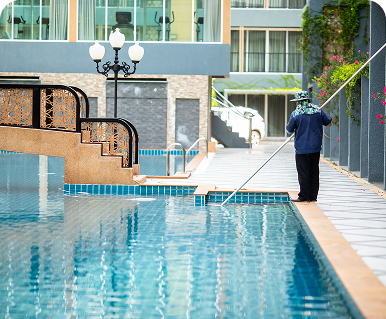 Person cleaning a pool with a net skimmer on a sunny day.