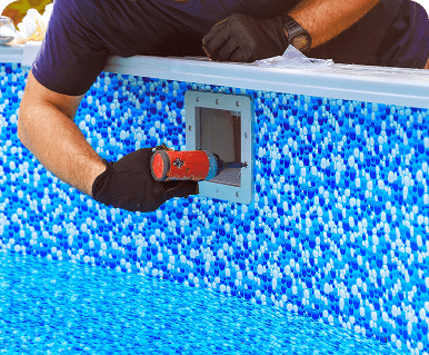 Person inspecting a pool wall with a flashlight.