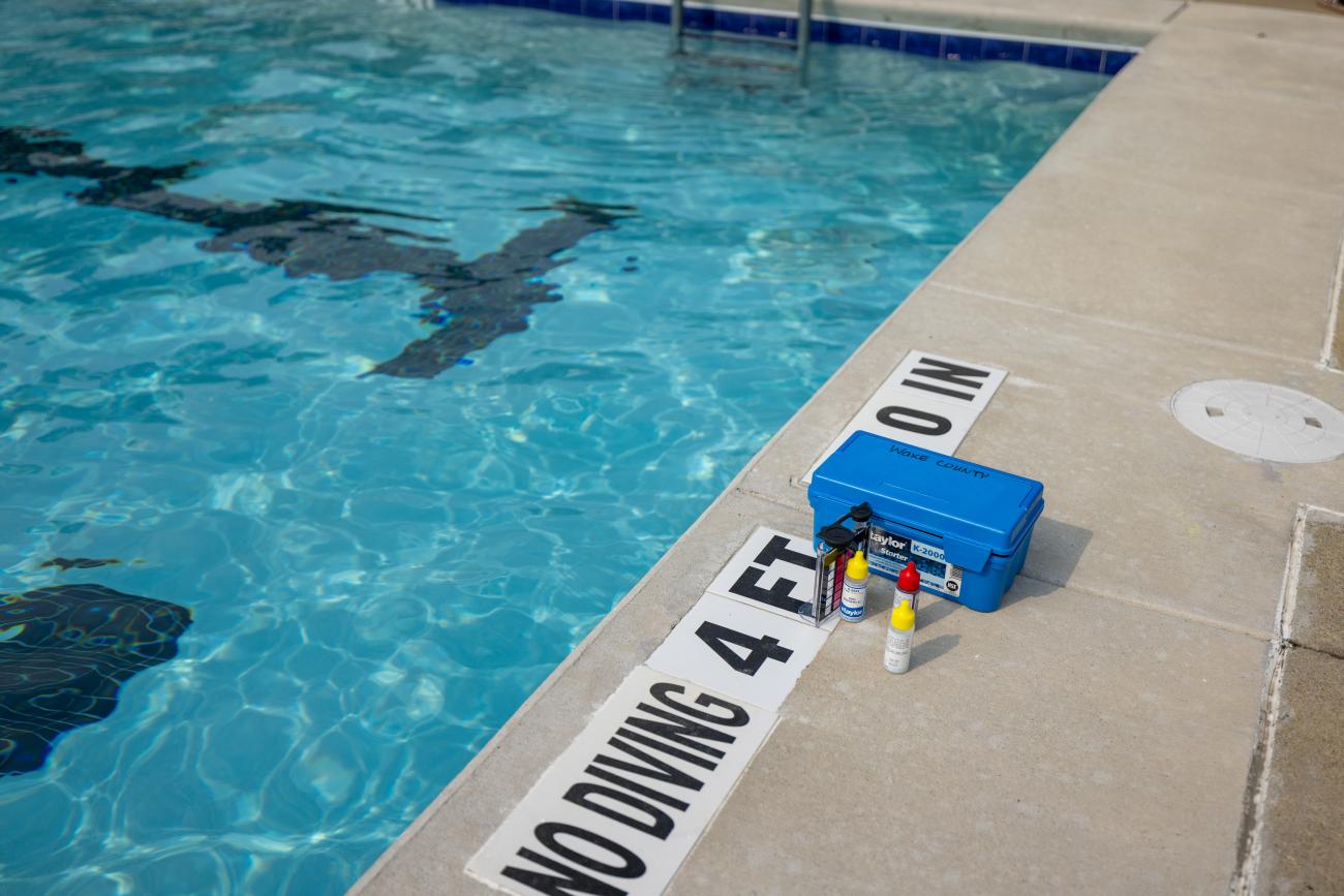 Poolside with a toy boat and a drink near the water's edge.
